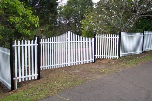White aluminium vertical picket fencing with black posts and a shaped top rail running along a footpath
